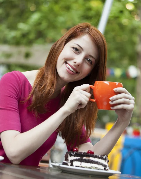 Стильная рыжая девушка с тортом и чашкой — стоковое фото