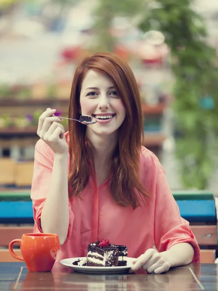 Стильная рыжая девушка с тортом и чашкой — стоковое фото