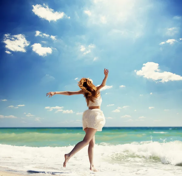 Junge rothaarige Mädchen springen am Strand. — Stockfoto