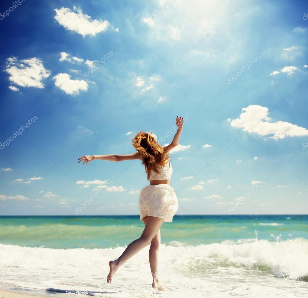 Young redhead girl jumping at the beach.