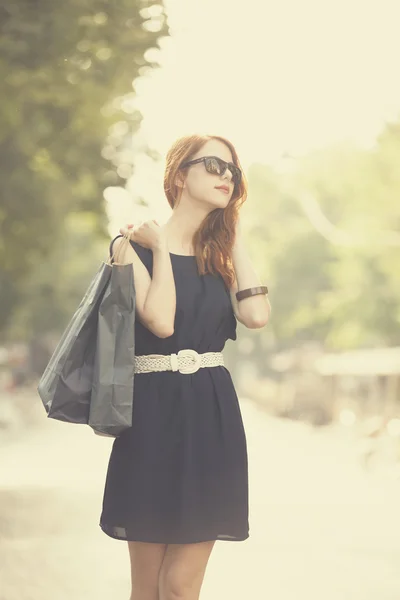 Giovane donna con borse della spesa a piedi sulla strada della città — Foto Stock