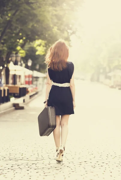 Молодая женщина с чемоданом на городской улице — стоковое фото