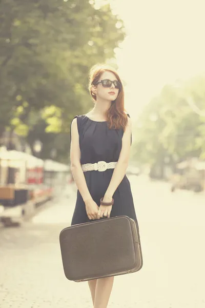 Mladá žena s kufrem na ulici města — Stock fotografie