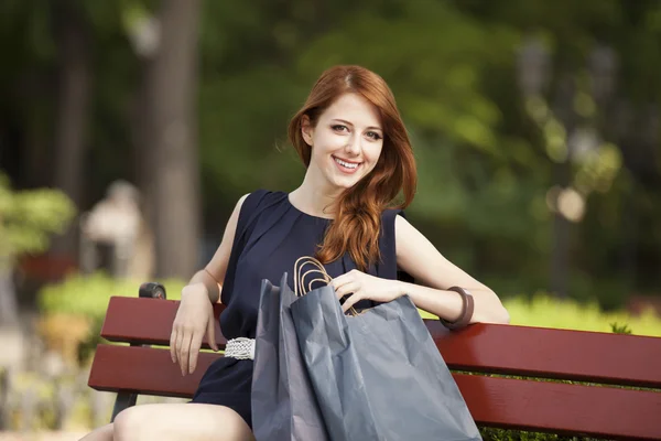Style rousse femmes assises sur le banc avec des sacs à provisions — Photo
