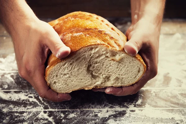 Mani di fornaio con un pane — Foto Stock