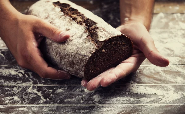 Baker's hands with a bread — Stock Photo, Image