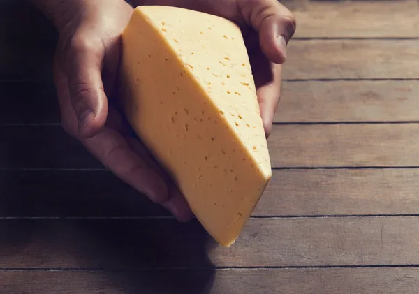 Farmář držet sýr v rukou nad dřevěný stůl — Stock fotografie