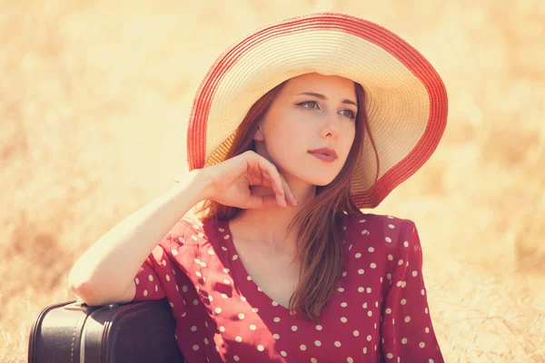 Roodharige meisje met koffer op gras zitten — Stockfoto