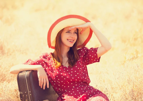 Redhead girl with suitcase sitting at grass — Stock Photo, Image