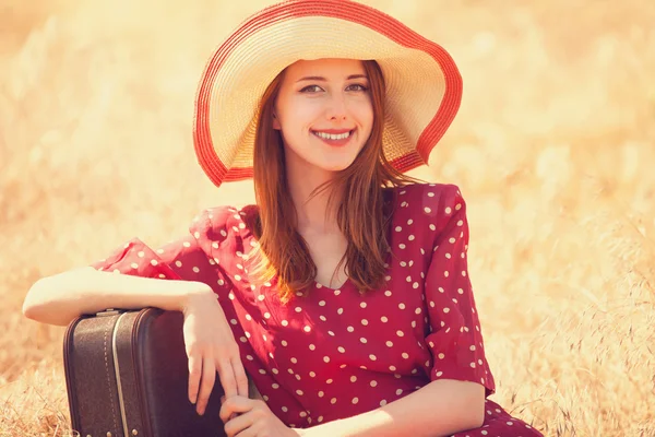 Roodharige meisje met koffer op gras zitten — Stockfoto