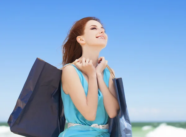 Pelirroja adolescente chica con bolsas de compras en la playa —  Fotos de Stock