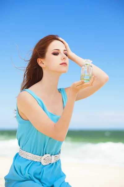 Roodharige meisje met parfum op het strand — Stockfoto