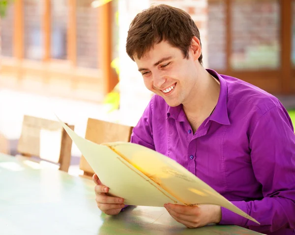 Young man sitting in the cafe and looking in the menu. — Stock Photo, Image