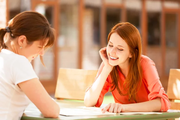 Two girls sitting in the cafe and looking in menu. — Stock Photo, Image