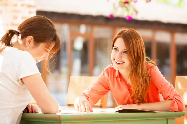 Two girls sitting in the cafe and looking in menu. — Stock Photo, Image