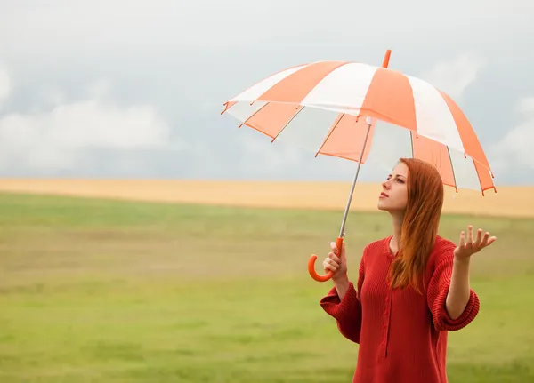 Redhead girl with umbrella at meadow — Stock Photo, Image