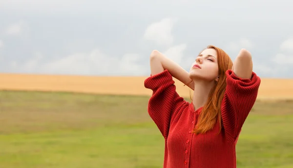 Ragazza rossa a prato vicino al campo di grano — Foto Stock