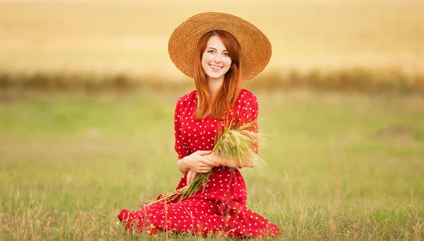 Fille rousse en robe rouge au champ de blé — Photo