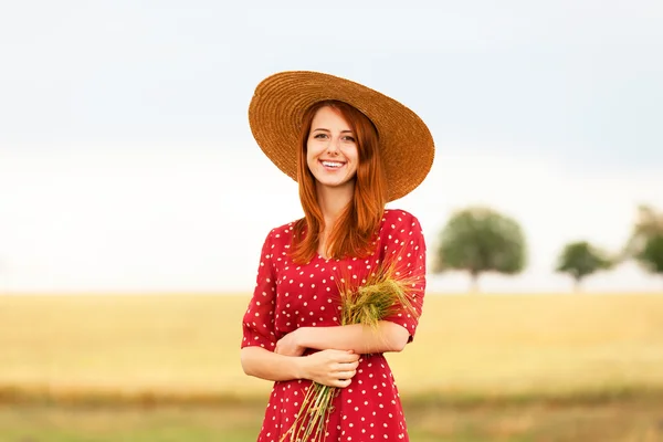 Rusovláska dívka v červených šatech v pšeničné pole — Stock fotografie