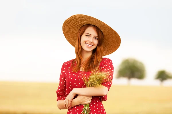 Fille rousse en robe rouge au champ de blé — Photo