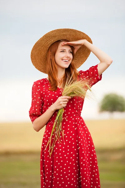 Menina ruiva em vestido vermelho no campo de trigo — Fotografia de Stock