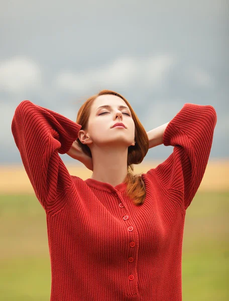 Рыжая девушка на лугу рядом с пшеничным полем — стоковое фото