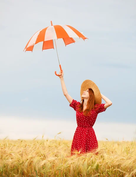Rödhårig tjej med paraply på vete fält — Stockfoto