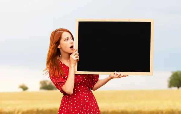 Roodharige meisje met schoolbord aan het tarweveld — Stockfoto