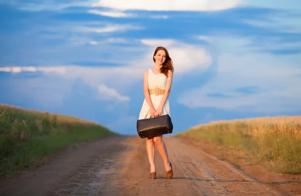 Rödhårig tjej med resväska på utomhus. — Stockfoto