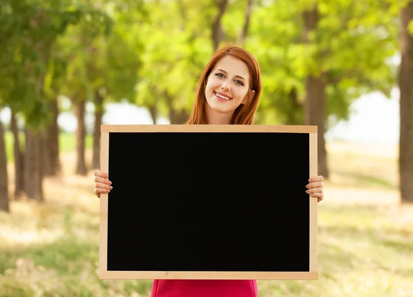 Roodharige meisje met schoolbord op buiten — Stockfoto
