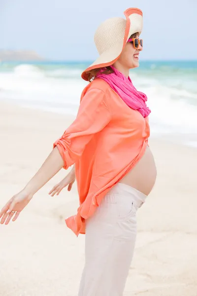 Schöne schwangere Frau am Strand sieht glücklich aus — Stockfoto