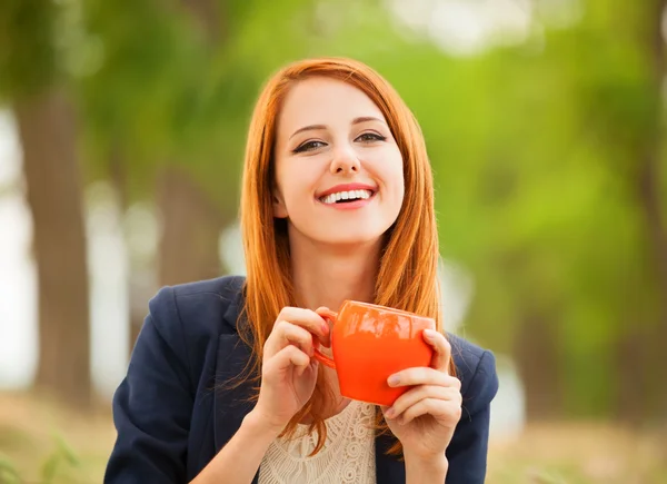 Rothaarige Mädchen mit orangefarbener Tasse im Freien — Stockfoto