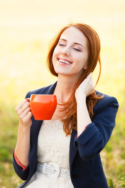 屋外でのオレンジ色のカップと赤毛の女の子 — ストック写真