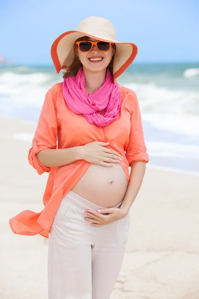 Schöne schwangere Frau am Strand sieht glücklich aus — Stockfoto