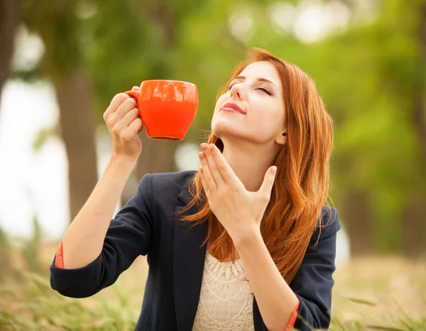 Pelirroja con taza naranja al aire libre — Foto de Stock