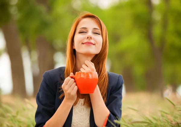 Rothaarige Mädchen mit orangefarbener Tasse im Freien — Stockfoto