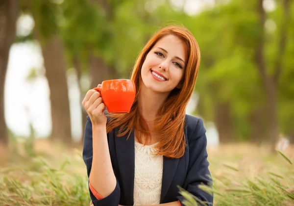 Rödhårig tjej med orange cup på utomhus — Stockfoto