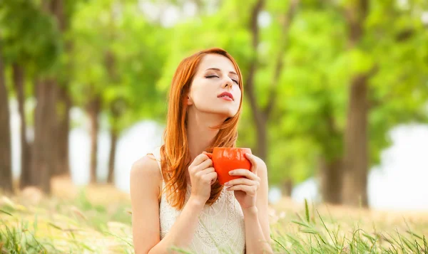 Roodharige meisje met oranje cup op buiten — Stockfoto