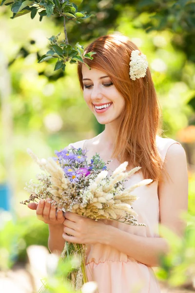 Rödhårig tjej med blommor på utomhus. — Stockfoto