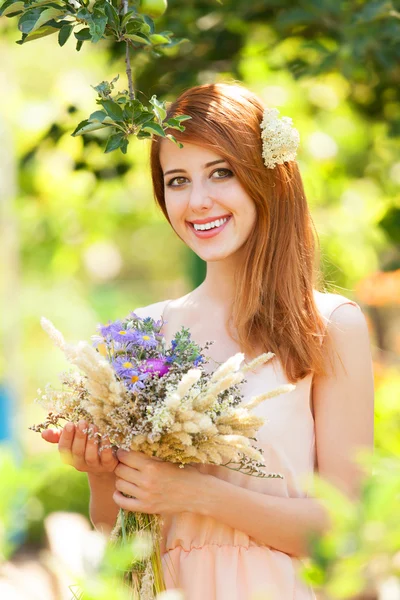 Roodharige meisje met bloemen bij buiten. — Stockfoto