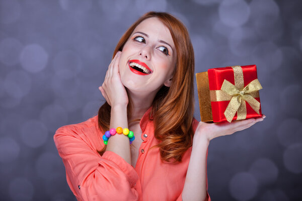 Redhead girl with present box. Bokeh.