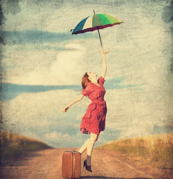 Fille rousse avec parapluie et valise à l'extérieur — Photo