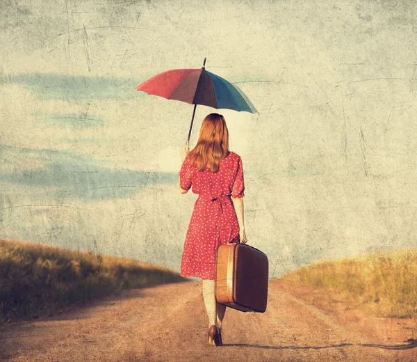 Roodharige meisje met paraplu en koffer in buiten — Stockfoto