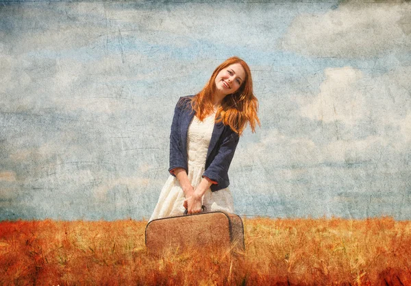 Redhead girl with suitcase at spring wheat field. — Stock Photo, Image