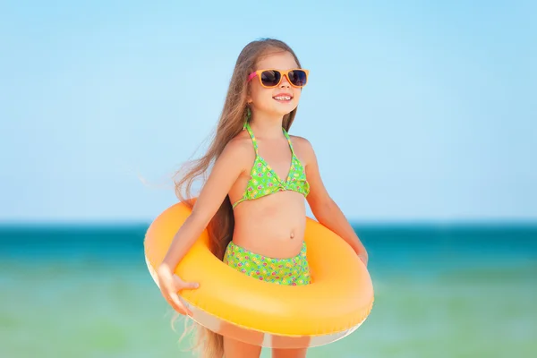 Bambino con occhiali da sole e anello gonfiabile in spiaggia — Foto Stock