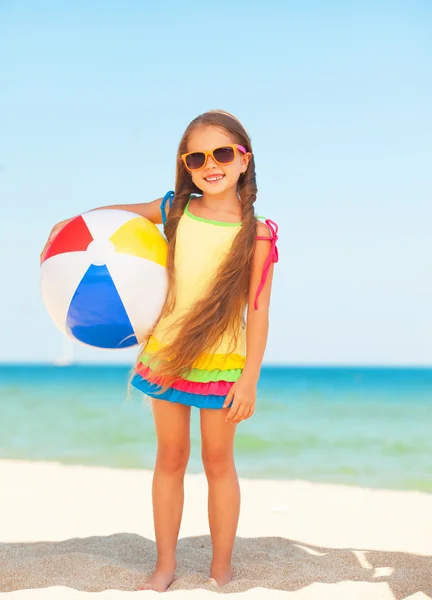 小さな女の子がボールとビーチで遊んで. — ストック写真