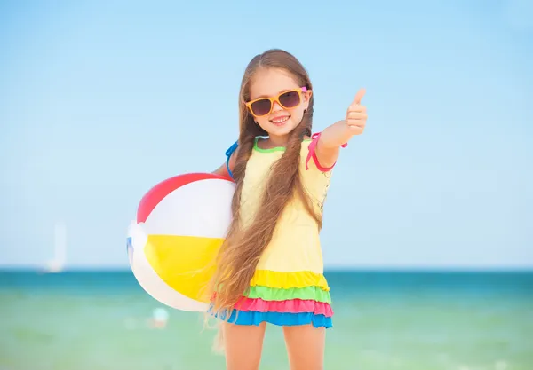 小さな女の子がボールとビーチで遊んで. — ストック写真