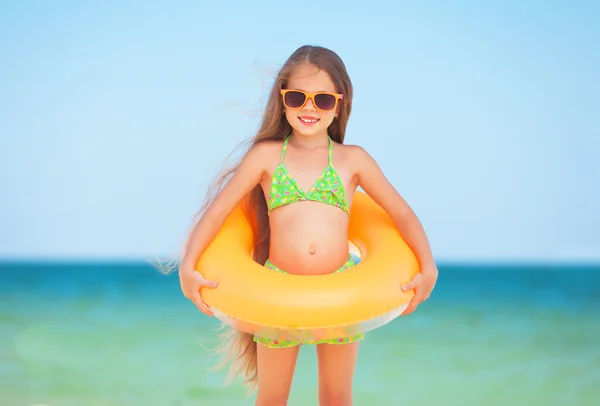 Bambino con occhiali da sole e anello gonfiabile in spiaggia — Foto Stock