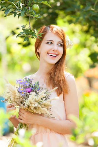 Roodharige meisje met bloemen bij buiten. — Stockfoto