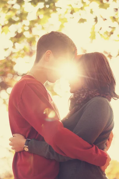 Um casal vai beijar-se no parque ao pôr-do-sol. Foto em multicolor — Fotografia de Stock